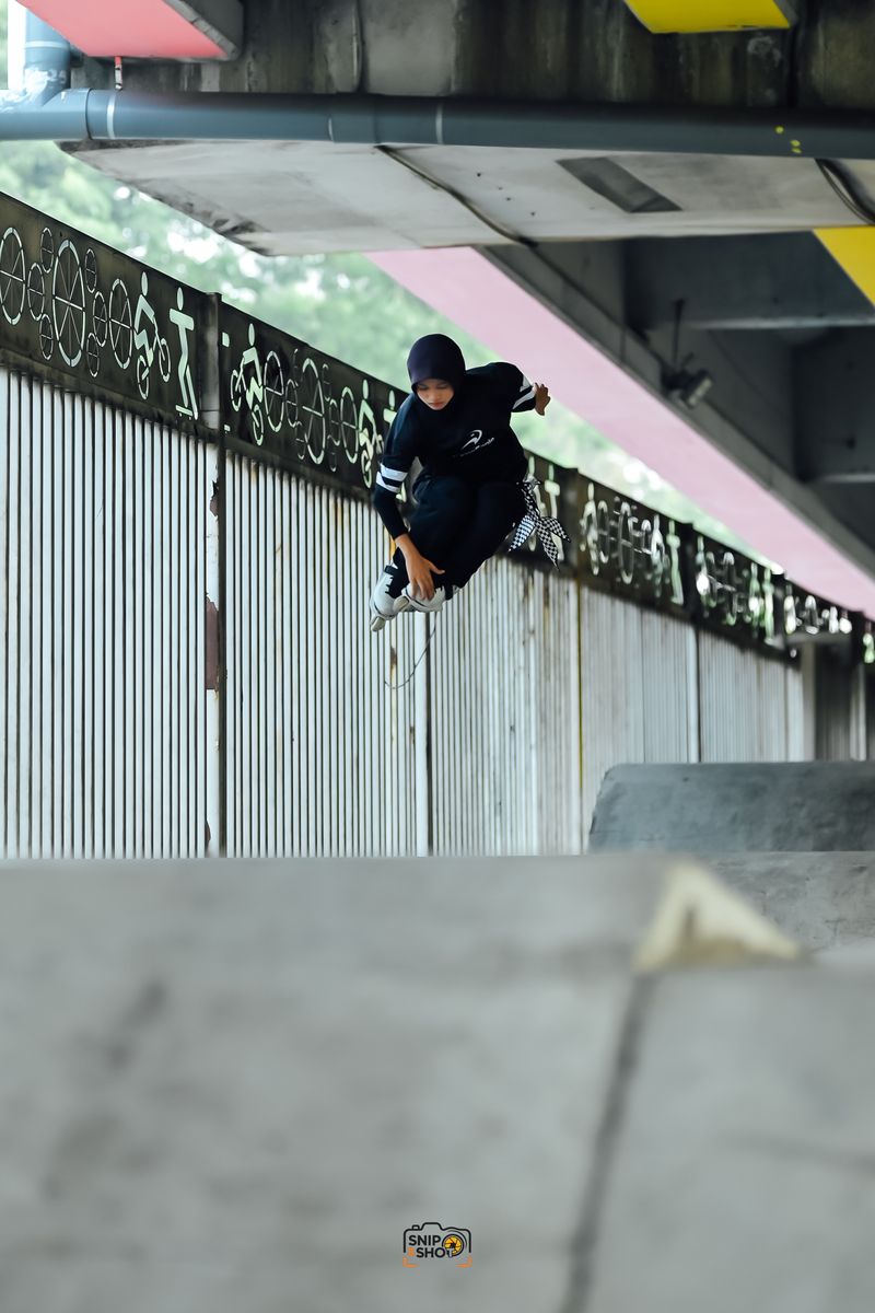 Inline skater holding a grab in mid-air beside a metal railing