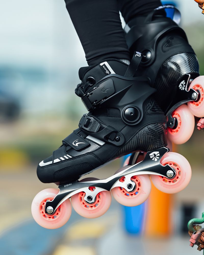 Close-up of black inline skates with pink wheels lifted above the ground