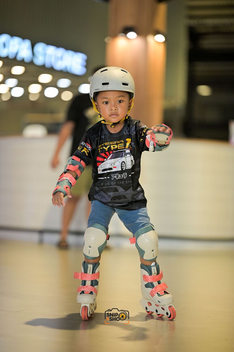 Young inline skater in a helmet and protective pads concentrating on balance