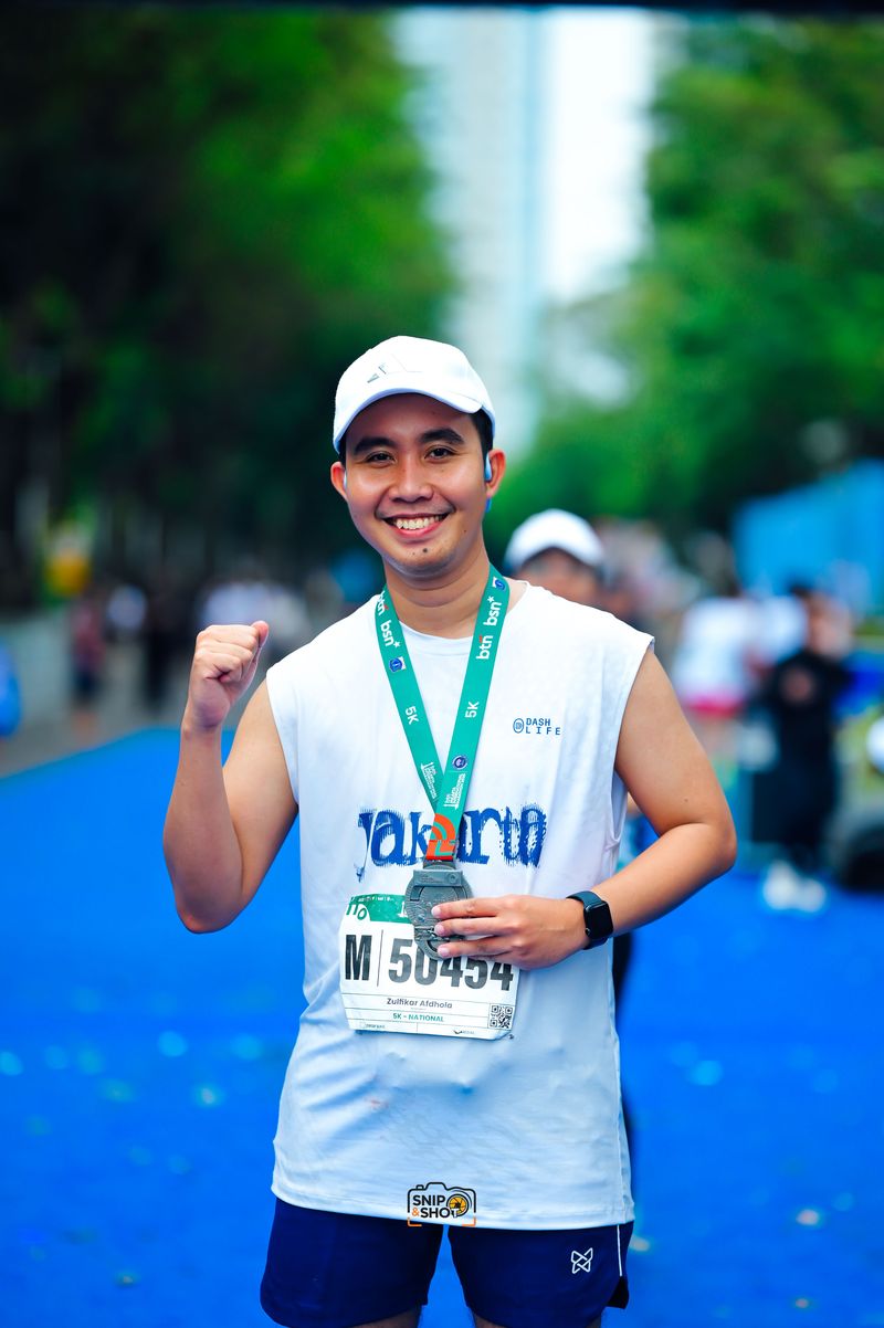 Smiling runner holding a finisher medal and raising a fist