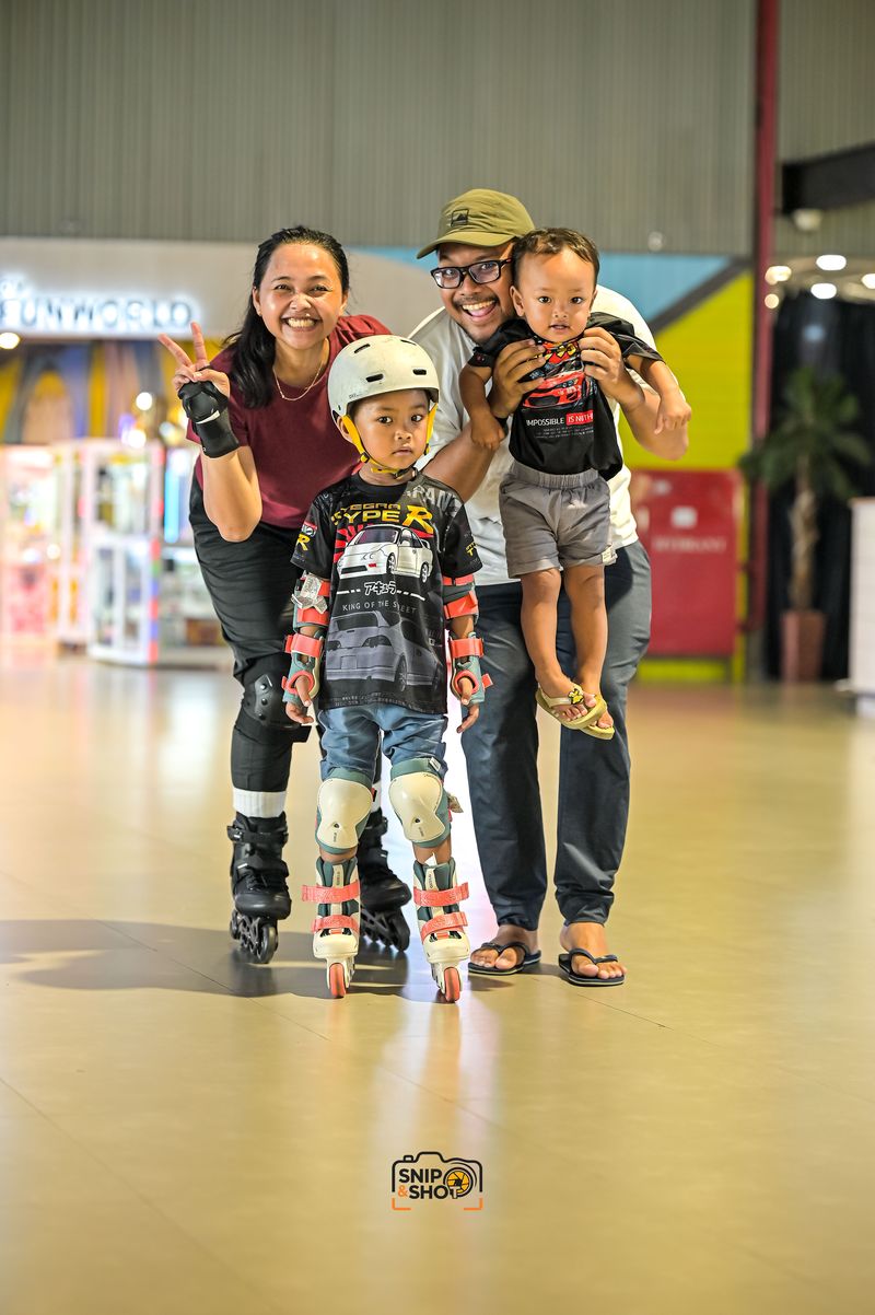Two adults and two children posing together around a young inline skater