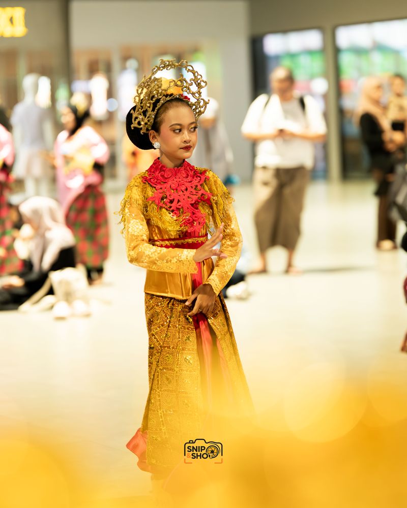 Young dancer in a gold and red costume with soft golden foreground blur