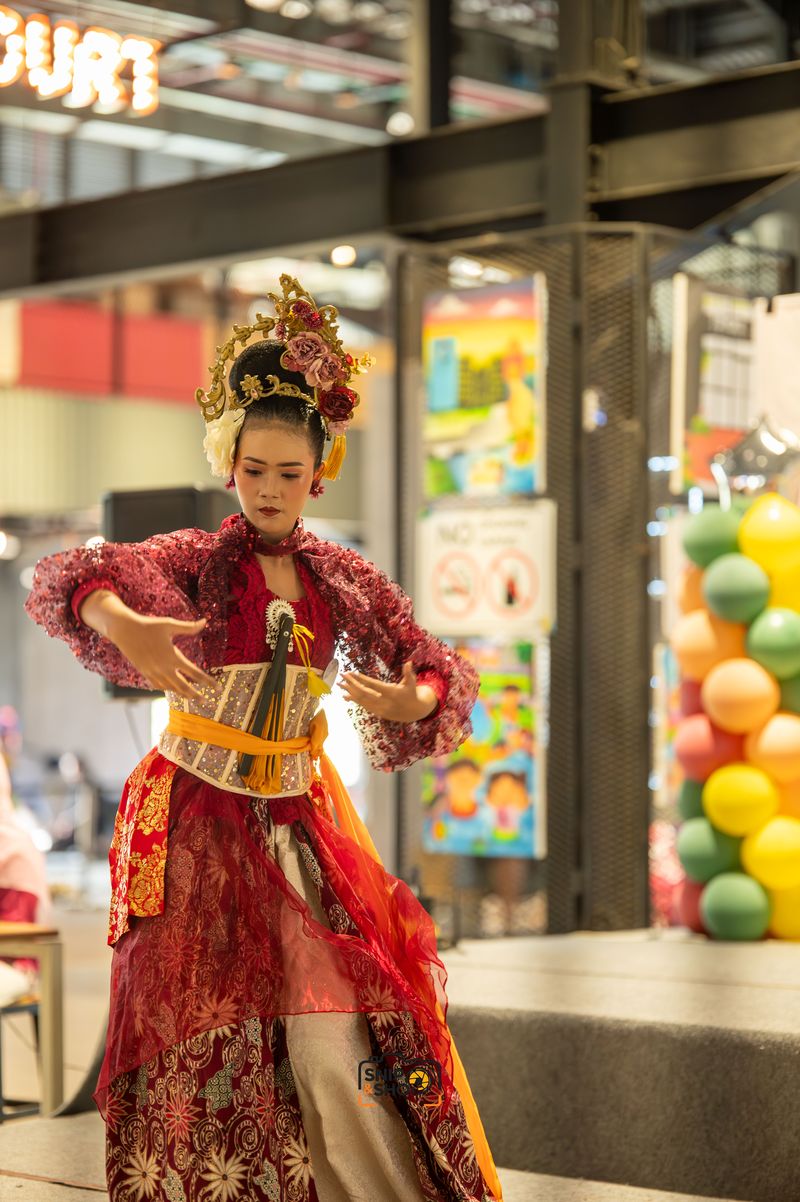Dancer in a red and gold costume forming an expressive hand gesture